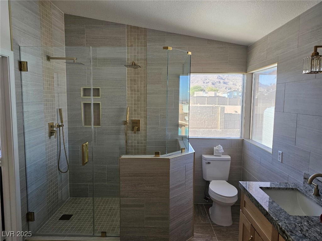 104 Appian Way Henderson, NV 89002 - Photo 28 of 52 Bathroom with tile walls, vanity, a shower stall, lofted ceiling, and a textured ceiling