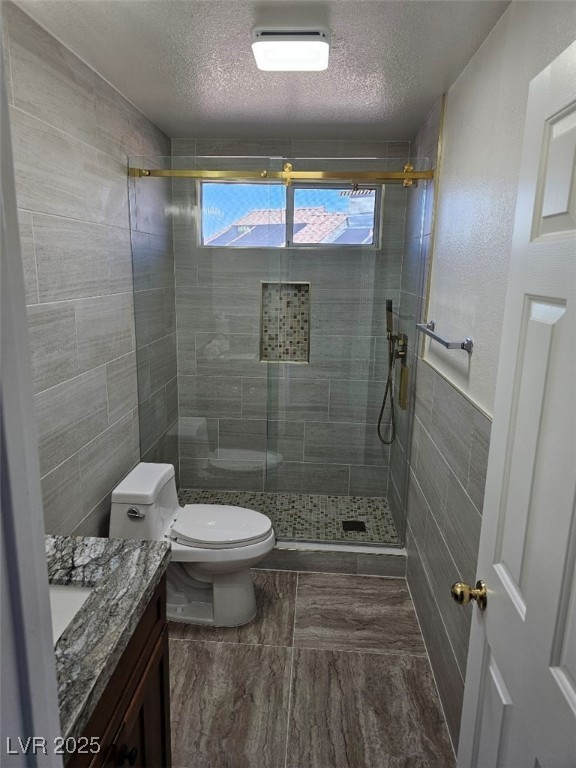 104 Appian Way Henderson, NV 89002 - Photo 33 of 52 Bathroom featuring tile walls, vanity, a textured ceiling, and a shower stall