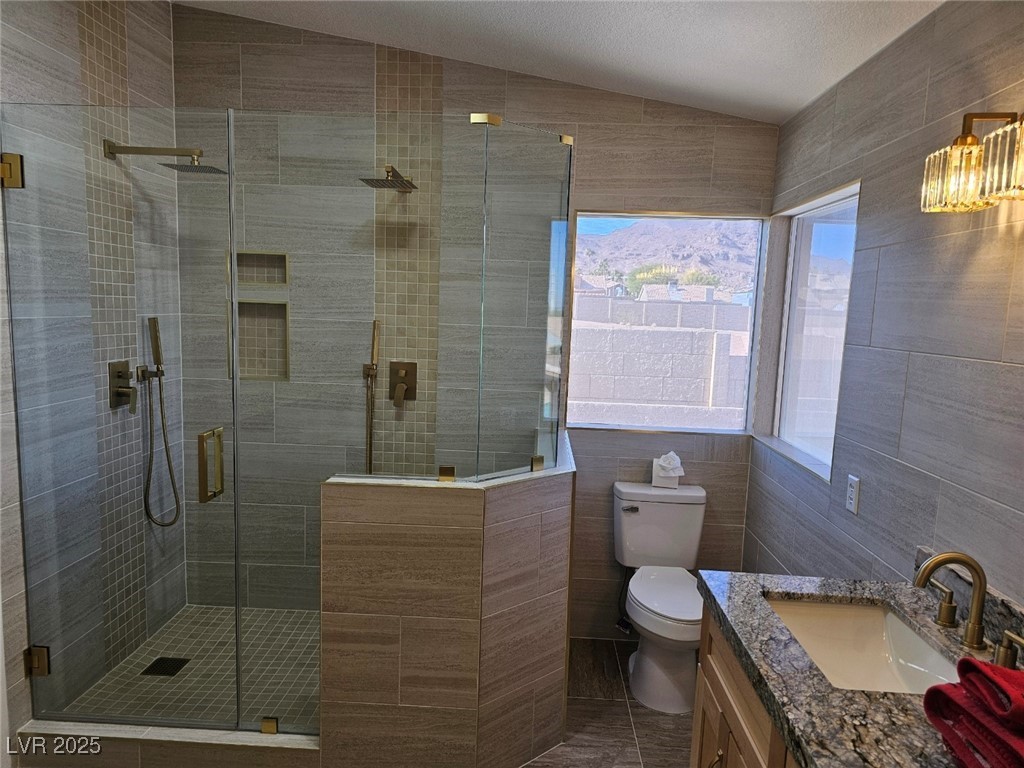 104 Appian Way Henderson, NV 89002 - Photo 41 of 52 Bathroom with tile walls, vanity, a stall shower, vaulted ceiling, and dark tile patterned flooring