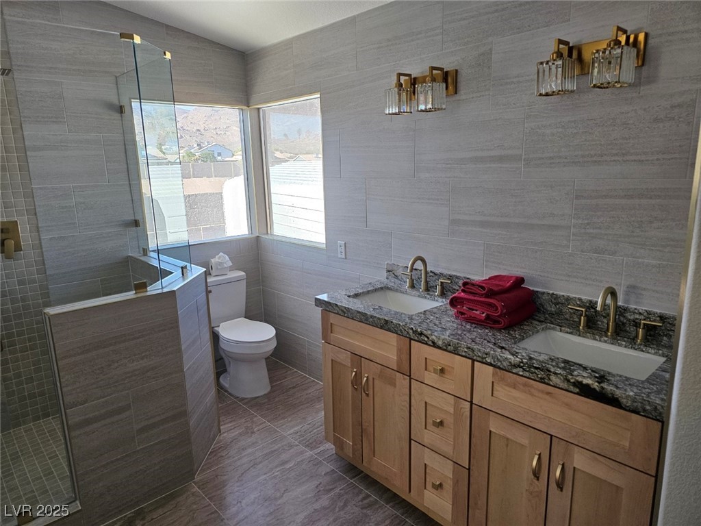 104 Appian Way Henderson, NV 89002 - Photo 42 of 52 Full bathroom featuring tile walls, double vanity, walk in shower, and backsplash