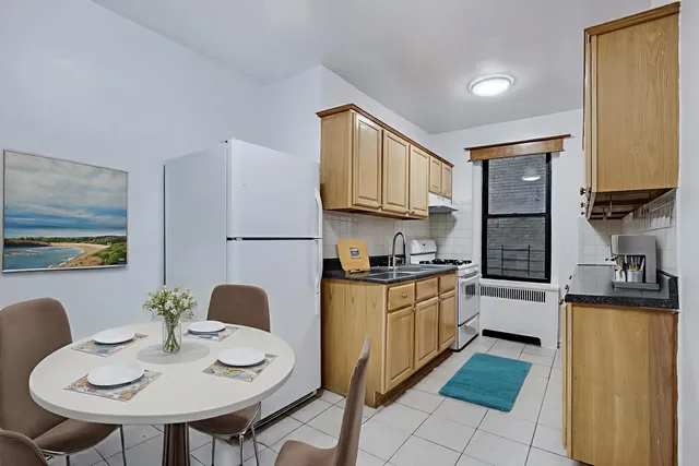 a kitchen with stainless steel appliances granite countertop a stove a sink a refrigerator a dining table and chairs