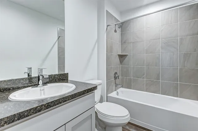 a bathroom with a granite countertop sink a toilet a mirror and bathtub