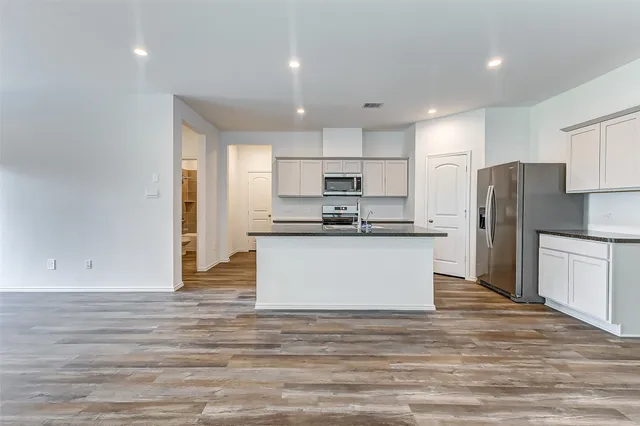 a kitchen with stainless steel appliances granite countertop a refrigerator sink and white cabinets