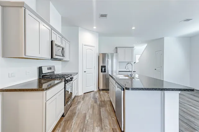 a kitchen with stainless steel appliances granite countertop a stove a sink and a refrigerator