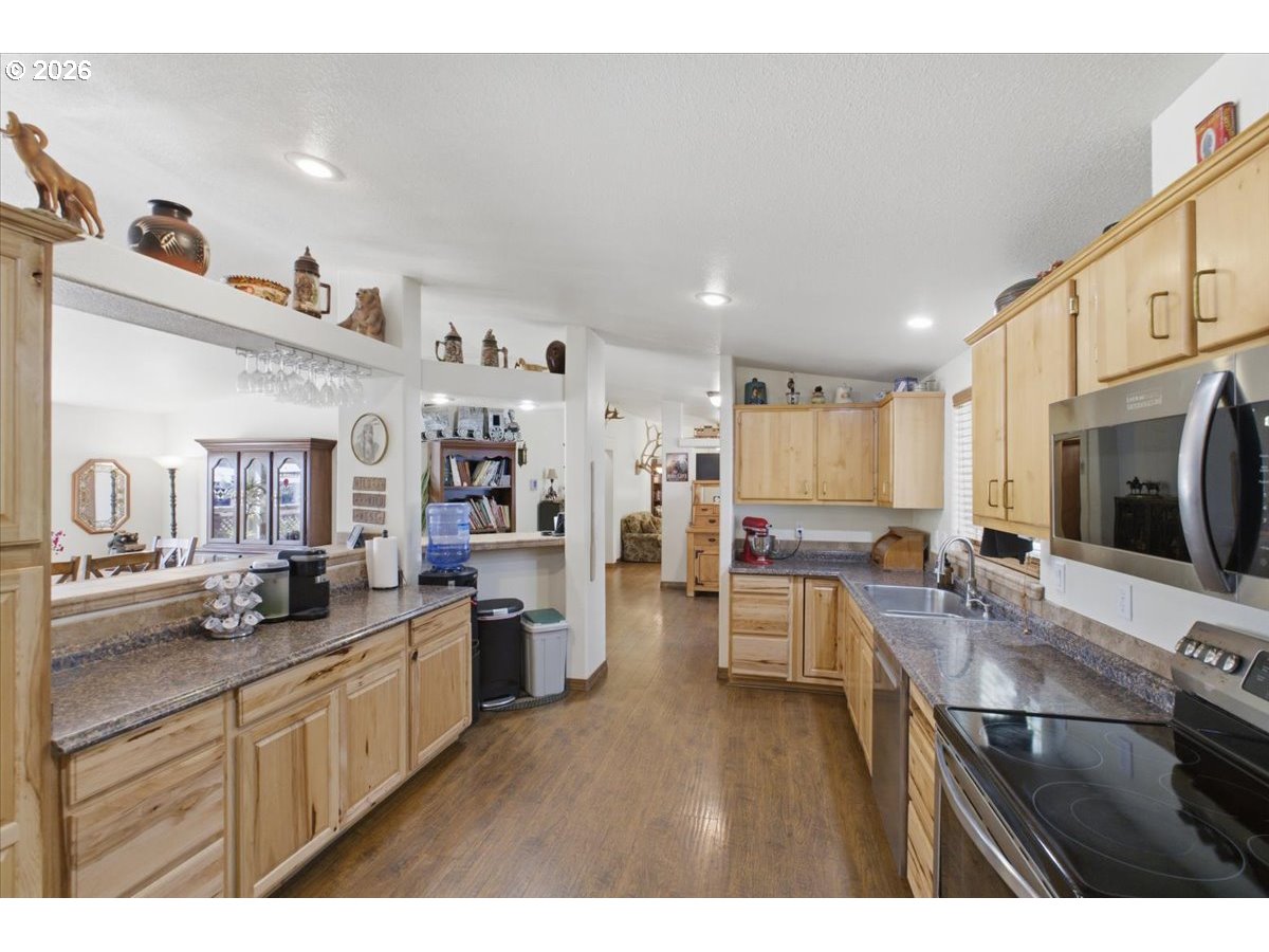 35377 Ede Road Lebanon, OR 97355 - Photo 11 of 48 a kitchen with stainless steel appliances kitchen island granite countertop a sink dishwasher stove and white cabinets with wooden floor
