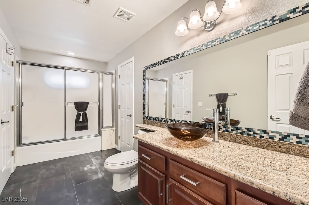 647 Foxhall Road Henderson, NV 89002 - Photo 28 of 82 Full bath featuring vanity, toilet, bath / shower combo with glass door, tile patterned floors, and visible vents