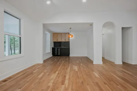 a view of empty room with wooden floor and kitchen