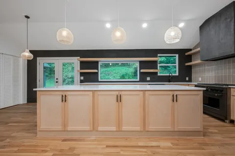 a kitchen with stainless steel appliances granite countertop a sink and a large window
