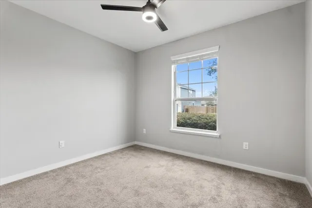 an empty room with a window and a ceiling fan