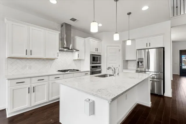 a kitchen with stainless steel appliances granite countertop a sink a stove a refrigerator and white cabinets
