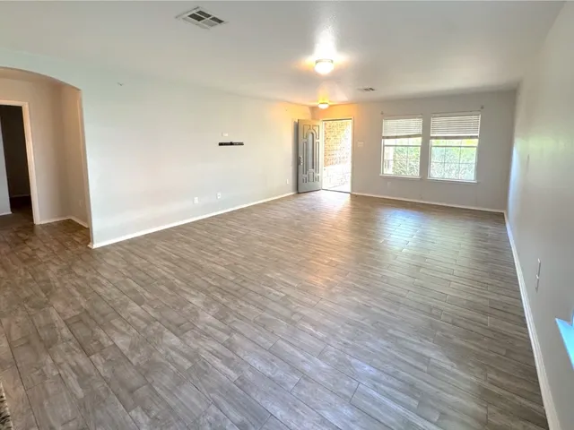 an empty room with wooden floor and windows with curtains view
