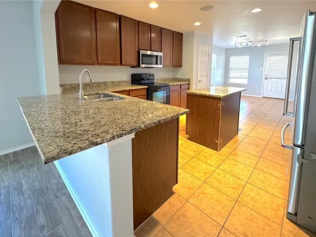 a kitchen with stainless steel appliances granite countertop a sink a stove and a microwave