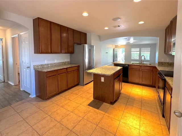 a large kitchen with kitchen island a sink a counter top stainless steel appliances and cabinets