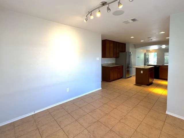 a view of an empty room and a kitchen