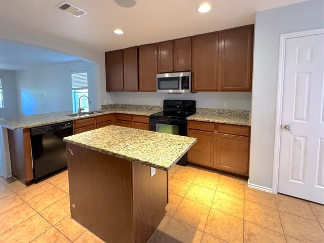 a kitchen with stainless steel appliances granite countertop a stove a sink and a microwave
