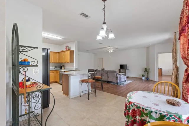 a kitchen with stainless steel appliances granite countertop a refrigerator a sink a stove and chairs with wooden floor