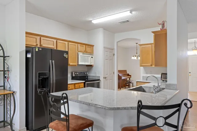 a kitchen with stainless steel appliances granite countertop a sink dishwasher stove and refrigerator with wooden floor