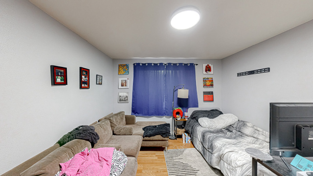 630 1100 West Provo, UT 84601 - Photo 21 of 64 Light gray walls featuring a single window with blue curtains, wood-finish flooring, and a flush-mount ceiling light fixture