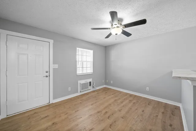 an empty room with windows and fan