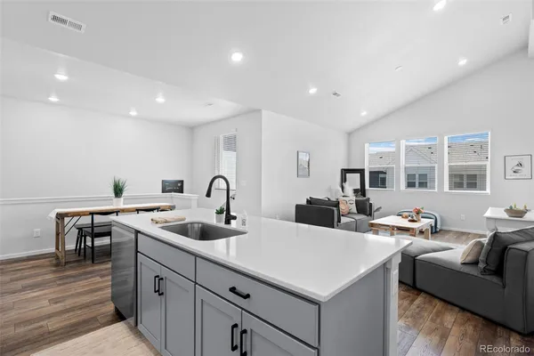 a kitchen that has a sink and a stove with wooden floor
