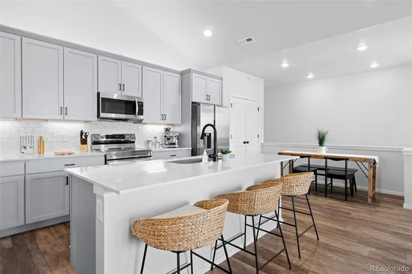 a kitchen with stainless steel appliances granite countertop a table chairs microwave and sink