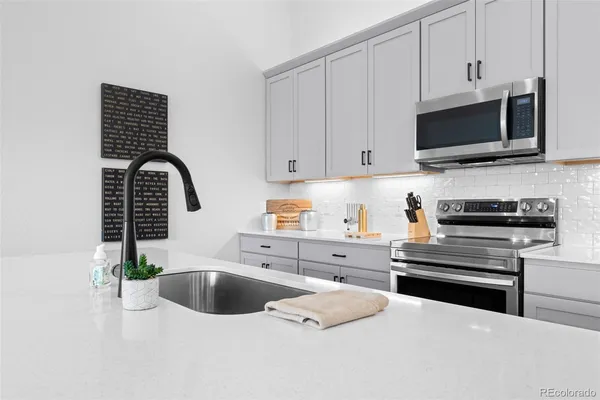 a kitchen with stainless steel appliances a stove a sink and a microwave