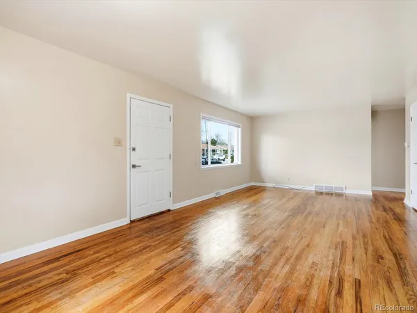 an empty room with wooden floor and windows