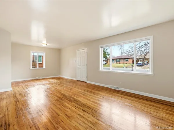 a view of an empty room with wooden floor and a window