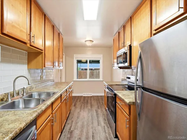 a kitchen with granite countertop a sink stove and refrigerator
