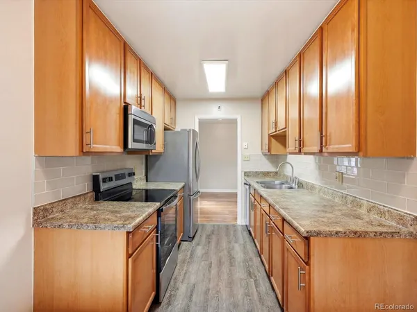 a kitchen with stainless steel appliances granite countertop a sink a stove and a refrigerator