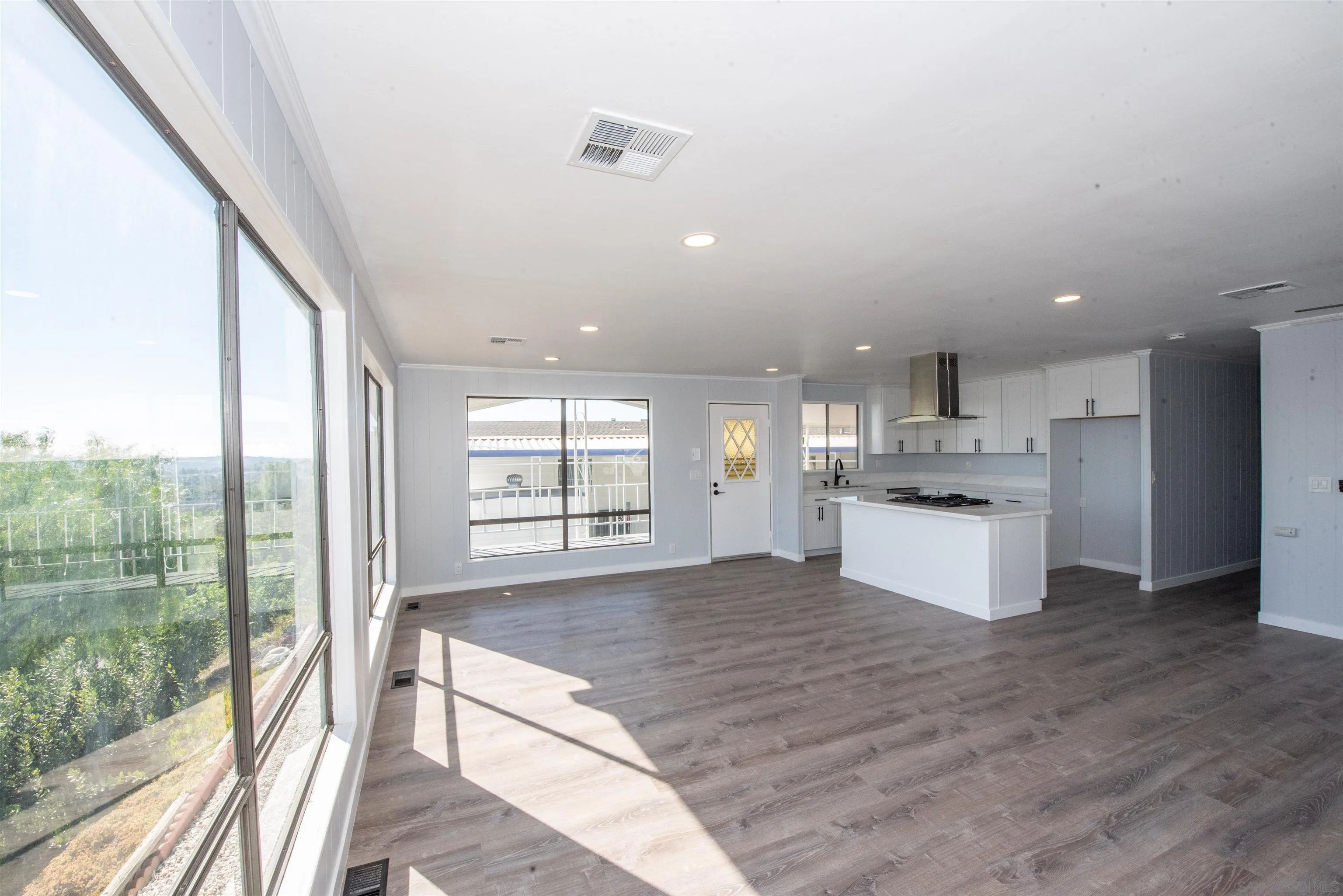 275 South Worthington Street, Unit 36 Spring Valley, CA 91977 - Photo 11 of 44 a large kitchen with kitchen island a stove a sink dishwasher and white cabinets with wooden floor next to a large window