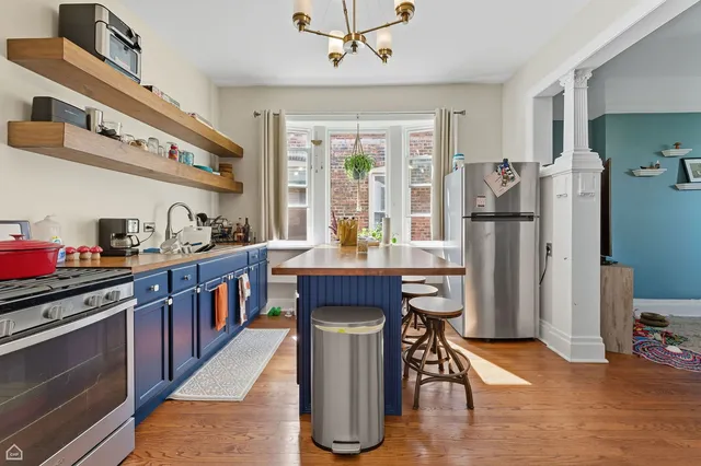 a kitchen with stainless steel appliances granite countertop a refrigerator a sink dishwasher a stove and a dining table with wooden floor