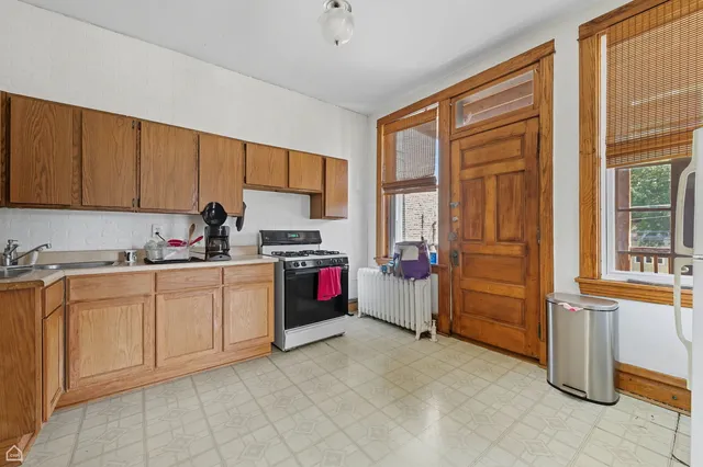 a open kitchen with cabinets a sink and a stove next to a window