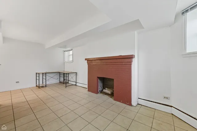 a view of an empty room with window and fire place