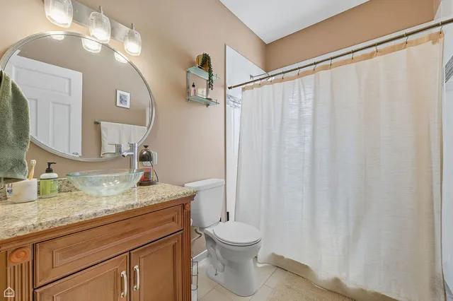 a bathroom with a granite countertop sink vanity mirror and toilet
