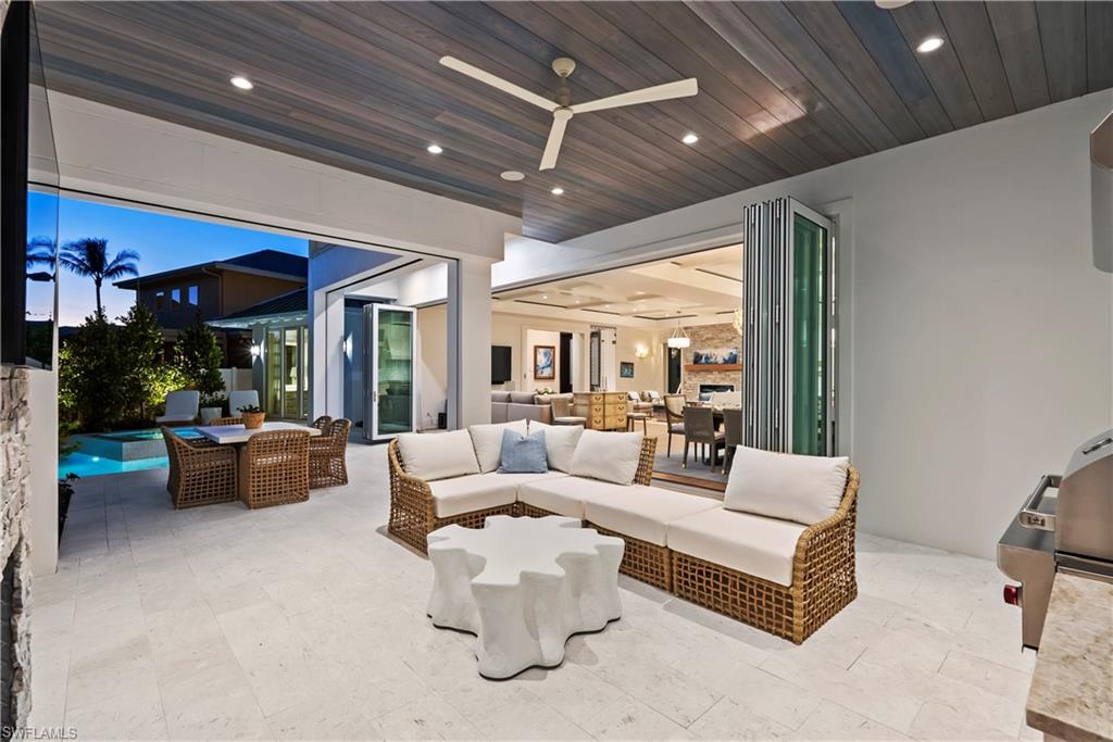 690 7th Avenue North Naples, FL 34102 - Photo 24 of 28 Patio terrace at dusk with exterior kitchen, an outdoor hangout area, and ceiling fan