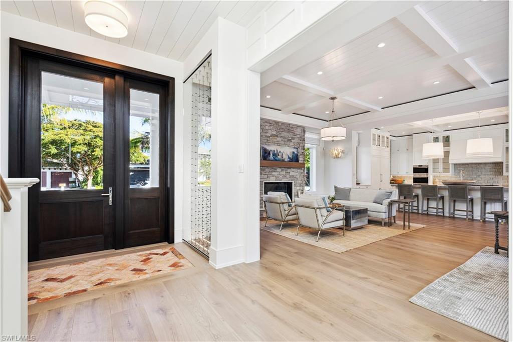 690 7th Avenue North Naples, FL 34102 - Photo 4 of 28 Foyer with a stone fireplace, beamed ceiling, coffered ceiling, wooden ceiling, and light wood-type flooring