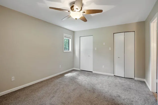 an empty room with windows and a ceiling fan