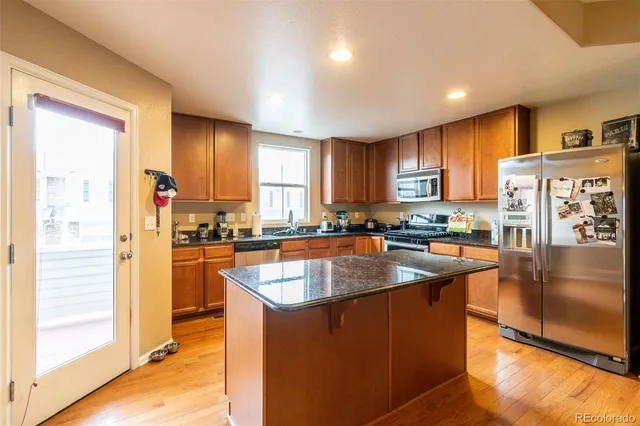 a kitchen with stainless steel appliances granite countertop a refrigerator a sink and a stove