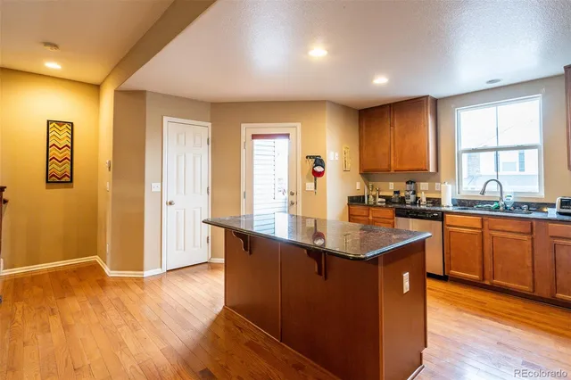 a kitchen with stainless steel appliances granite countertop a sink dishwasher a stove and a refrigerator