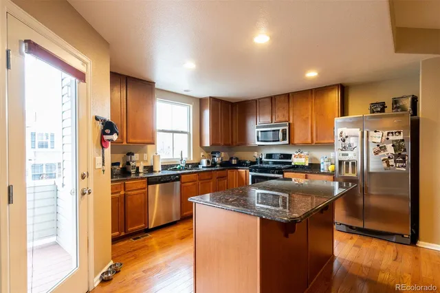 a kitchen with stainless steel appliances granite countertop a refrigerator a stove top oven a sink and dishwasher
