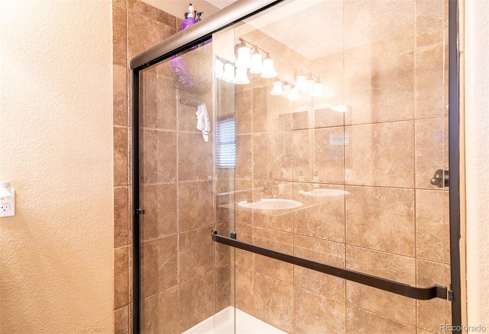 2681 Stonecrop Ridge Grove Colorado Springs, CO 80910 - Photo 19 of 26 a bathroom with a glass shower door