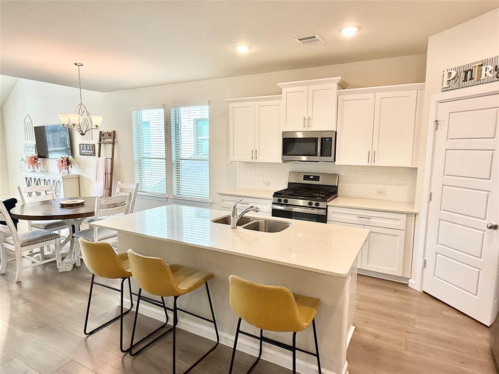 603 Hazeltine Road Red Oak, TX 75154 - Photo 9 of 37 a kitchen with a stove a sink a microwave a dining table and chairs