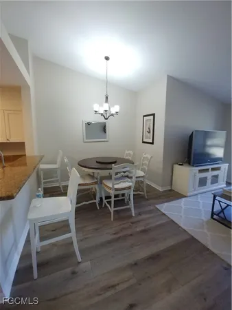 a dining room with wooden floor a chandelier a wooden table and chairs