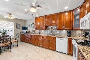 a kitchen with stainless steel appliances granite countertop wooden cabinets a sink a stove a dining table and chairs