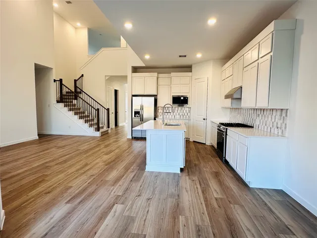 a kitchen with counter top space a sink wooden floor and stainless steel appliances