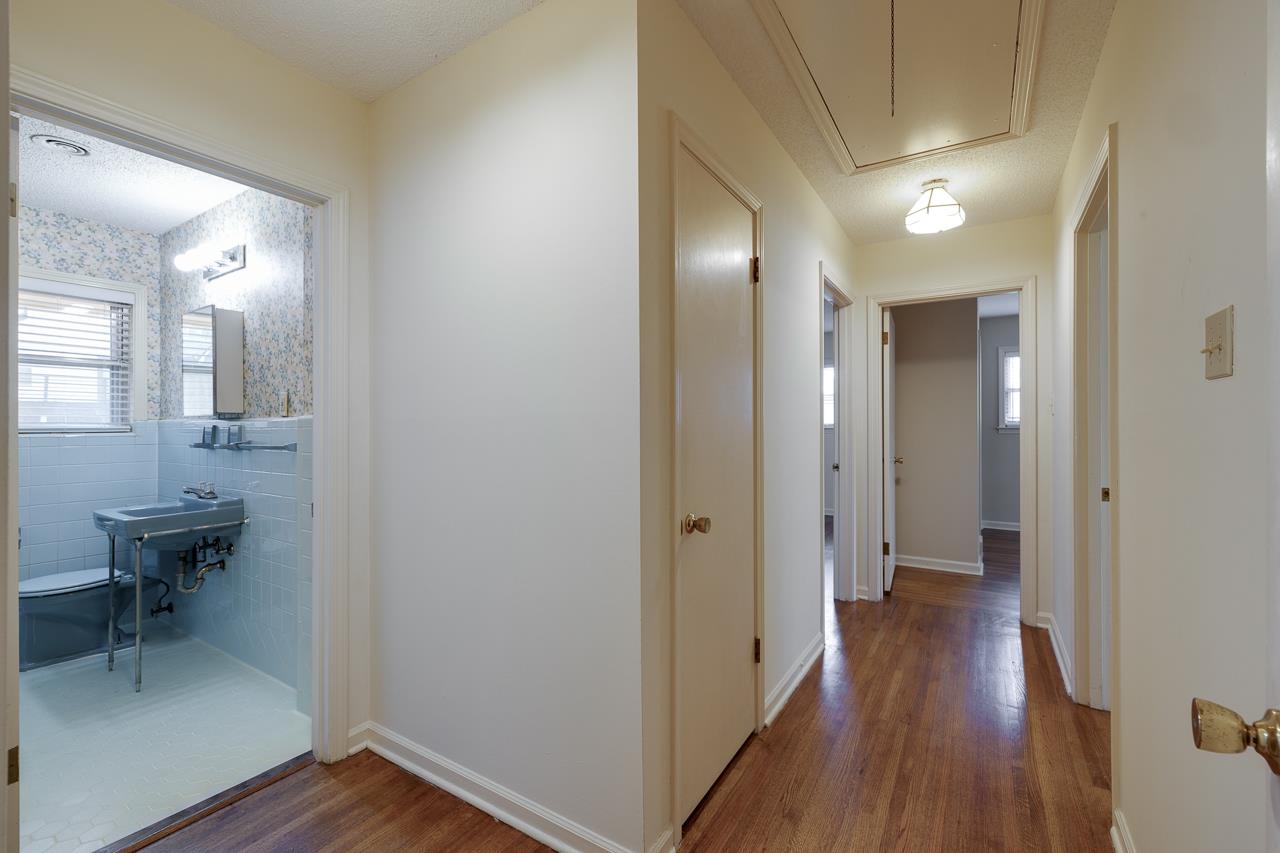 5673 Normandy Road Memphis, TN 38120 - Photo 21 of 39 a view of a hallway with wooden floor and a bathroom