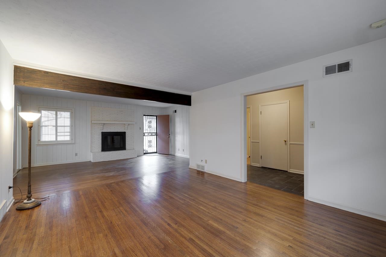 5673 Normandy Road Memphis, TN 38120 - Photo 9 of 39 an empty room with wooden floor and fireplace