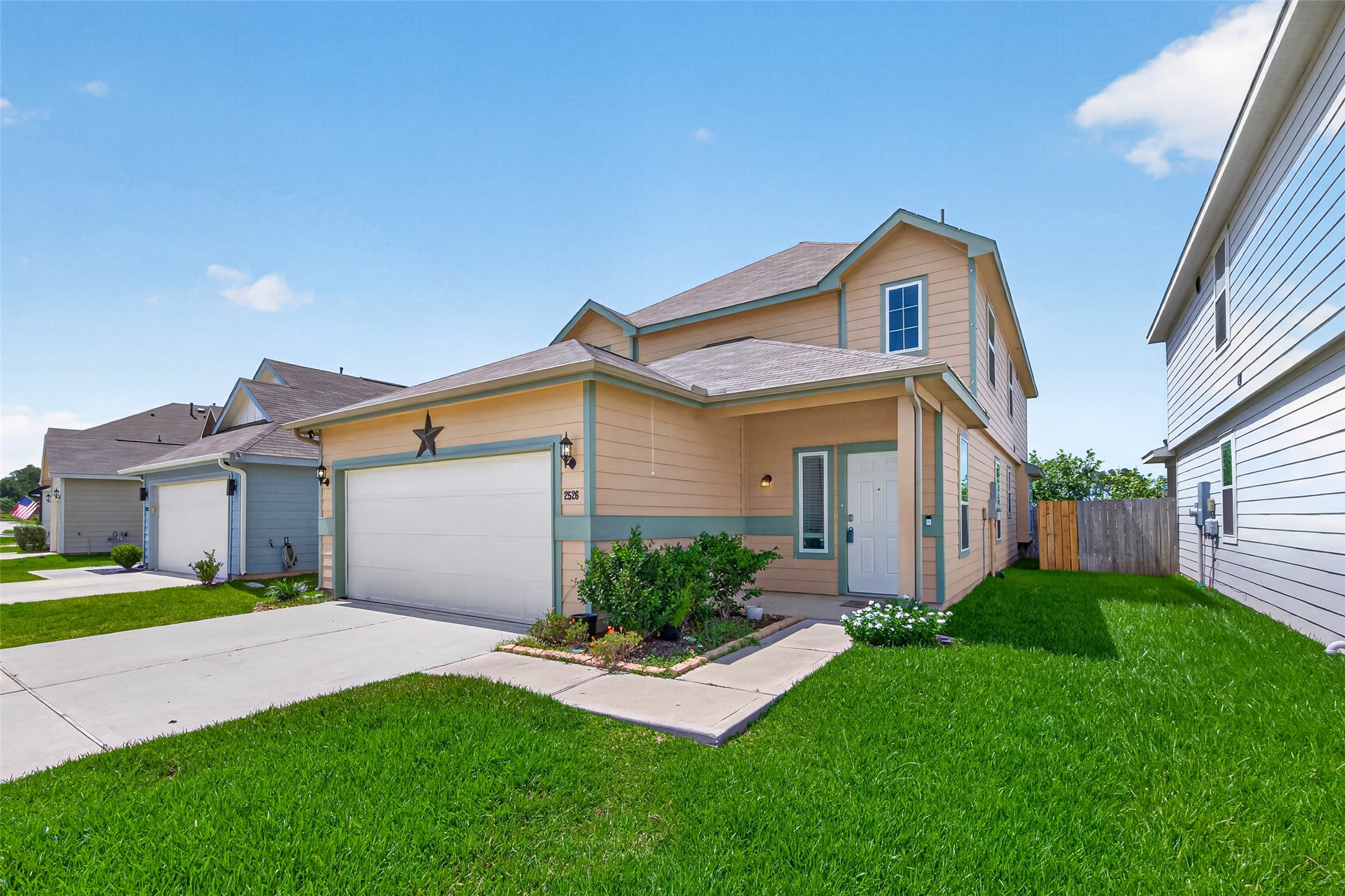 2526 Sturgeon Way Conroe, TX 77384 - Photo 2 of 49 This photo showcases a modern two-story home with a spacious two-car garage and well-maintained front yard. The exterior features a neutral color palette and a charming star accent. It's situated in a suburban neighborhood with similar style homes.