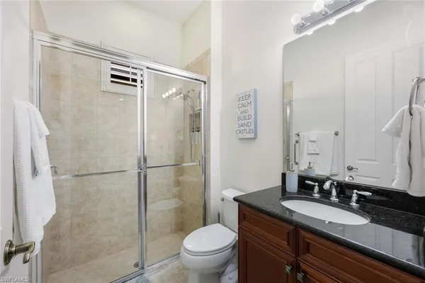 a bathroom with a granite countertop sink toilet a mirror and shower